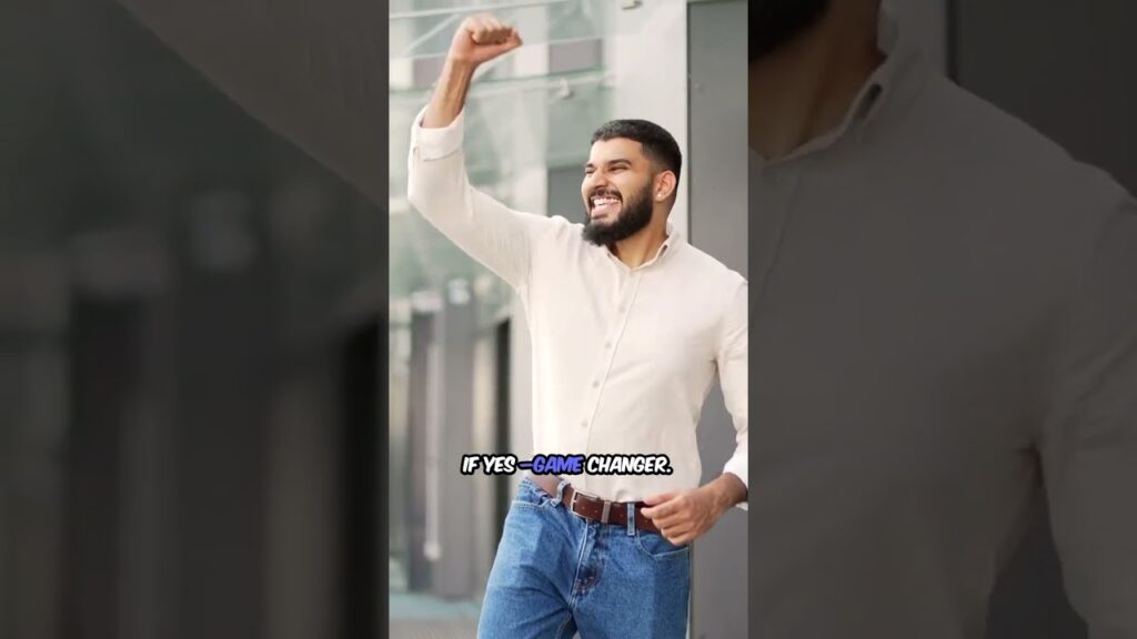 Man in a light-colored shirt celebrating with a raised fist and a smile, standing outdoors.